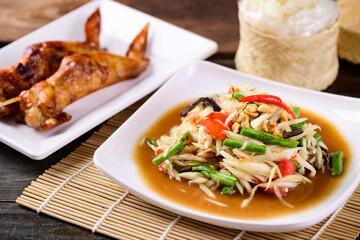 Thai food (Som Tum), Spicy green papaya salad eating with grilled chicken wing and sticky rice
