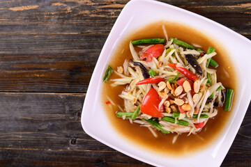 Thai food (Som Tum), Spicy green papaya salad on wooden background, Top view