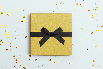 Beautiful festive white background with stylish golden gift box and confetti. Top view.