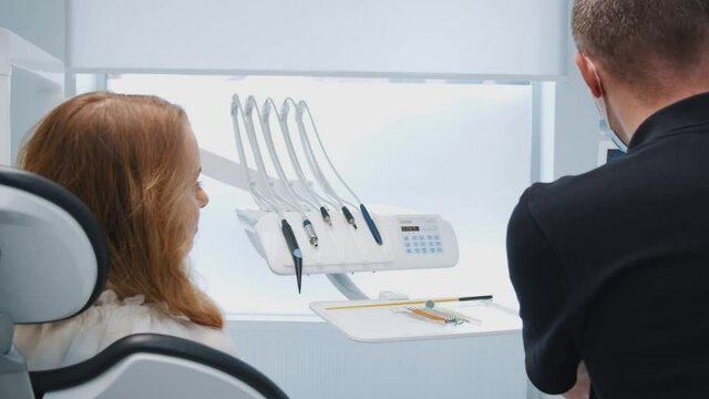 Young woman doing dental checkup in professional teeth clinic. Doctor orthodontist explaining diagnosis and treatment showing x-ray image. Orthodontist. Interiors.