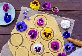 Fototapeta premium Shortcrust pastry dough decorated with natural edible flowers on dark wooden background