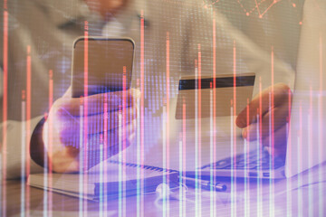 Double exposure of man hands holding a credit card and Forex graph drawing. Stock trading and digital fintech in Internet E-commerce concept.