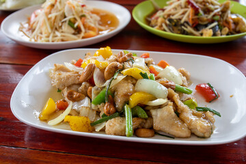 Thai food, chicken cashew nut in front, in the back two different papaya salads