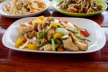 Thai food, chicken cashew nut in front, in the back two different papaya salads