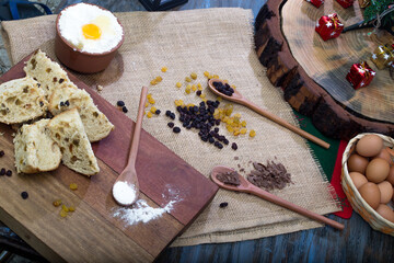 Christmas table. making panettone. with chocolate and raisin panettone. rustic table with wood and dark background. copy space