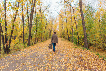 Fototapeta premium Tall handsome man with a bag on the autumn alley