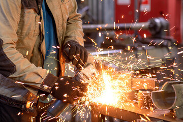 The worker cuts off the metal, many sparks fly in deferent directions