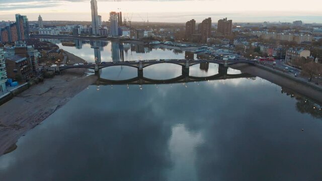 Falling crane drone shot of thames river traffic Battersea bridge and Chelsea harbour London at sunset