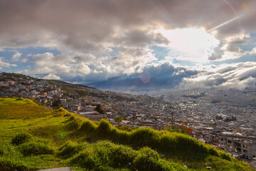 Fototapeta premium Sun shines through the clouds in Quito city in Ecuador 