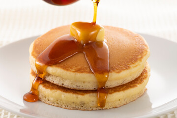 積み重ねたホットケーキにメープルシロップをかけて食べる