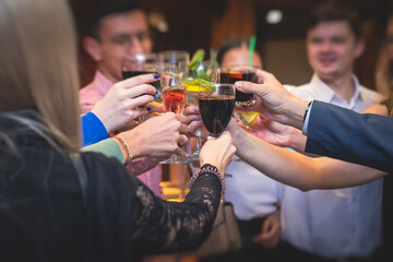 People celebrate and raise glasses, cheering with alcohol glasses with wine and champagne in the restaurant on corporate christmas birthday party event or wedding celebration
