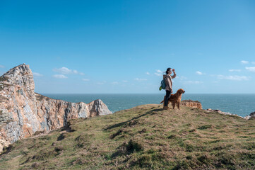 Golden Retriever and owner on a hilltop by the sea