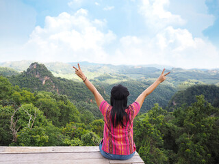 Fototapeta na wymiar woman tourist raise arms over rainforest mountain and blue sky background.