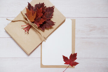 Colorful maple leaves and letter set on white wooden background. Autumn greeting.