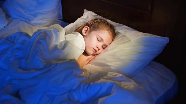 The pretty girl naps in bed, sees a pleasant sleep and smiles.