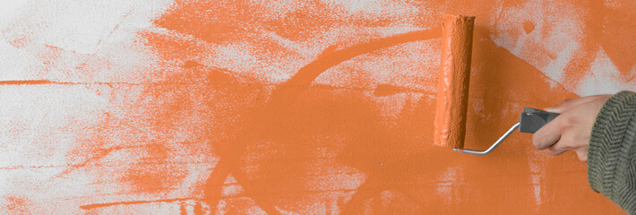 Painting the apartment, renovation with orange paint. close-up roller on the background of a bright...