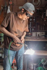 Welders stand up wearing black welding glasses when making metal racks in a welding shop