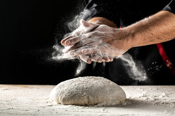 Hand clap of professional chef with bowl for cooking and baking utensils with splash flour on dark...