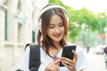 Beautiful Asian girl is using her phone to listen to music
