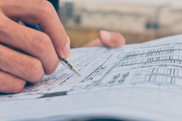 Close up hand write on paper blueprint checking building construction project