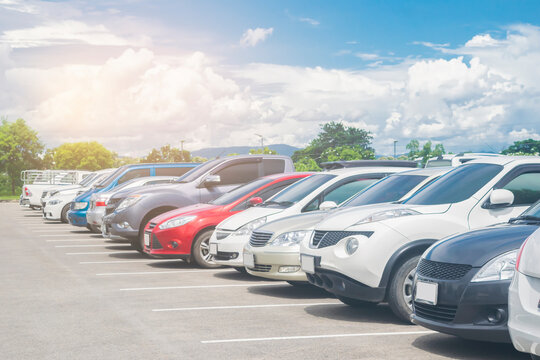 Fototapeta Car parked in large asphalt parking lot with beautiful cloud and blue sky background. Outdoor parking lot  travel transportation technology with nature