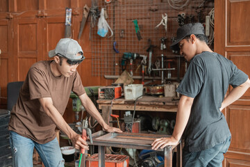 Male customer sees a welder working on a metal rack in a welding shop