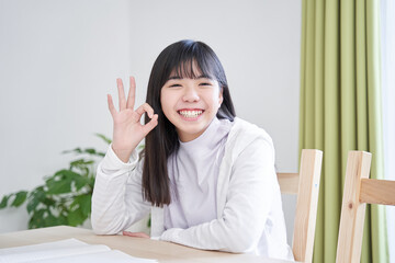 リビングで笑顔でOKサインを出す日本人女子中学生