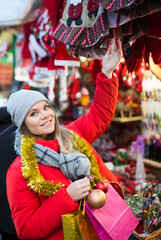 Young positive girl shopping decorations on traditional Christmas market in Spain