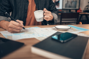 Fototapeta na wymiar Tourist hold cup of coffee and hand use pen for marking location and planing travel. Map, Coffee, Toast, Camera, Book, and Pen on the table. Tourist planning vacation-holiday with map.