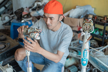 electronics repairman fixes a broken fan dynamo at an electronics repair shop