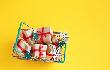 Christmas gifts and New Year decorations in a shopping basket on yellow background. - 393019262