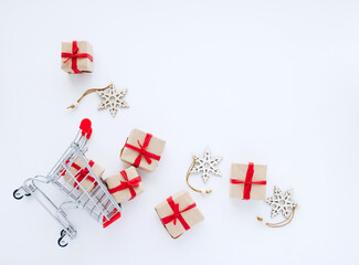 Top view on shopping cart with gifts and christmas decorations scattered on white background with copy space. Flat lay composition. - 393019287