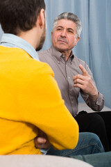 Fototapeta premium Adult father and son discuss family problems at home on couch