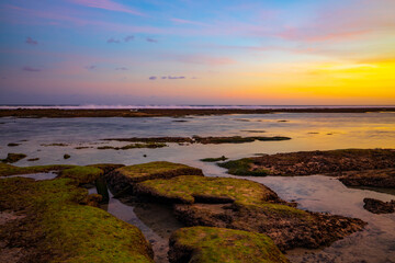 Seascape. Beach with rocks and stones. Low tide. Pink sunset. Slow shutter speed. Soft focus. Melasti beach, Bali, Indonesia