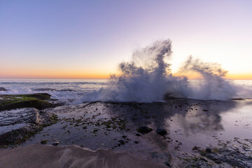 waves crashing on the rocky beach during sunset 