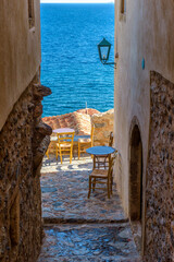 Traditional cafe exterior in the fortified medieval  castle of Monemvasia. Iron tables and wooden chairs  with the view of the  aegean sea in the background.