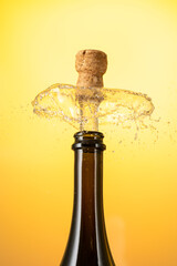 cork flies out of a bottle of champagne under pressure with stream and splash on colored background