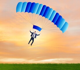 Young businessman falling on parachute in business concept