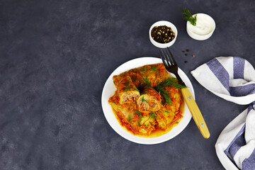 Stuffed cabbage with ground beef in tomato sauce on plate, closeup, view from above, with copy space.