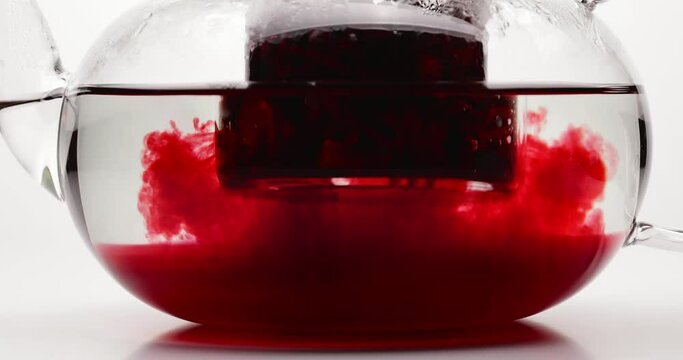 Brewing of tasty hibiscus tea in teapot against white background, closeup
