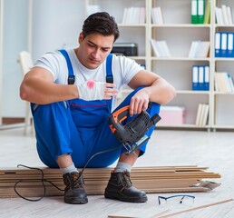 Young worker working on floor laminate tiles