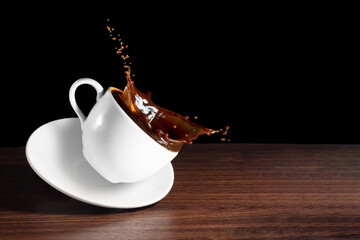 Coffee advertising design. Coffee beans, cup of tilted coffee with a splash effect  on brown desk