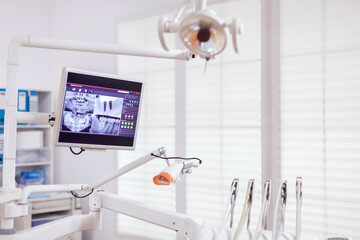 Dental instruments and tools in a dentist office. Stomatology cabinet with nobody in it and orange equipment for oral treatment.