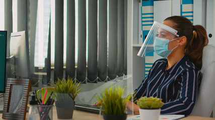 Entrepreneur with mask during coronavirus pandemic working in new normal business office discussing with coworker analysing financial data. freelancer respecting social distance in corporate company.