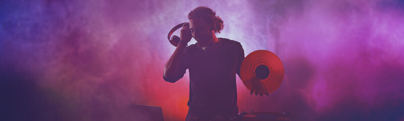 Silhouette of male dj playing music in nightclub