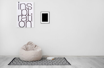 Stylish bean bag chair with books near light wall in room