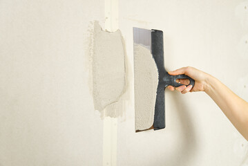 Woman putty plaster. Builder female indoor worker plastering wall with spatula trowel tool.