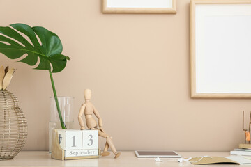 Wooden mannequin with calendar on table in room