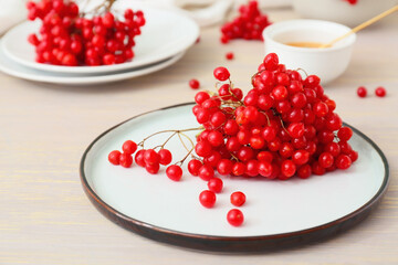 Plate with fresh viburnum berries on table