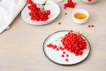 Plate with fresh viburnum berries on table